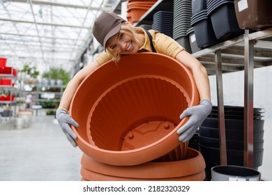 Smiling Female Garden Center Worker Hugging Huge Pot