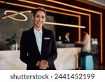 Smiling female hotel receptionist in a hallway looking at camera. Copy space. 