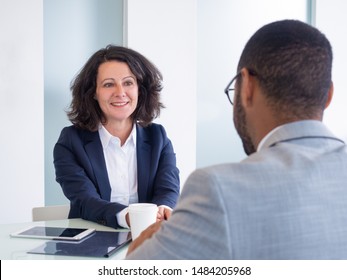 Smiling Female Job Candidate Talking To Employer During Interview. Business Man And Woman Sitting At Meeting Table And Talking. Career Concept