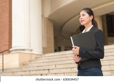 Smiling Female Lawyer Holding Legal Case File Information Thinking About How To Solve Problem Standing In Classical Court Outside Ladder.