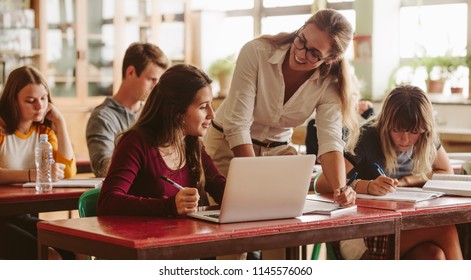 Smiling female lecturer helping student during her class. Student in a lecture with helpful teacher. - Powered by Shutterstock