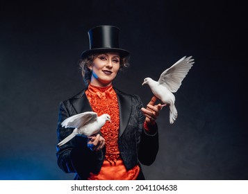 Smiling female magician with two white little doves in dark background - Powered by Shutterstock