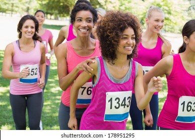 Smiling female participants of breast cancer marathon running in park