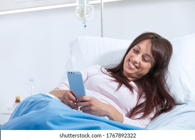 Smiling female patient lying in bed at the hospital and chatting with his smartphone - Powered by Shutterstock