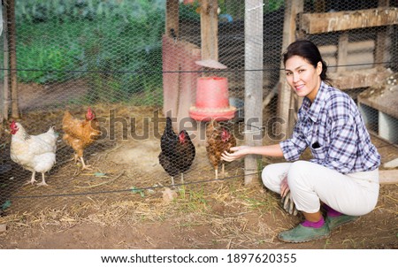 Smiling female proffesional farmer standing at chicken house at farm
