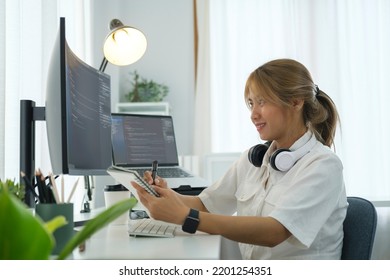 Smiling Female Programmers Sitting Front Of Large Curved  Computer Monitor And Writing Program Code At Modern Workplace.