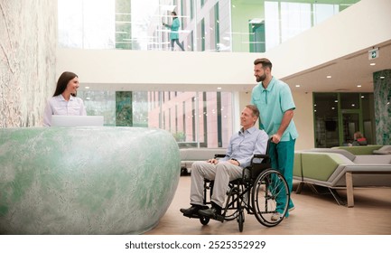 Smiling female receptionist in a modern clinic greets a patient in a wheelchair, assisted by a healthcare worker in scrubs. The bright, spacious lobby features comfortable seating and large windows. - Powered by Shutterstock