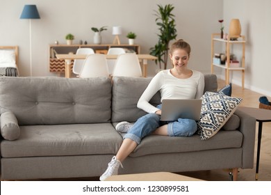 Smiling Female Sit On Cozy Couch At Home With Laptop On Knees Browsing Internet, Happy Girl Spend Weekend In Apartment Relaxing On Couch Watching Film On Computer, Woman Shopping Online