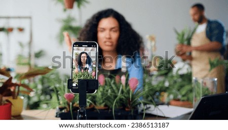 Smiling female social media blogger designer florist shooting new video on smartphone, talking about gardening and planting. Female gardener streaming live video, conference calling or making creative