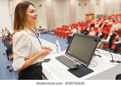 Smiling female speaker on stage talking at business seminar in convention center - Powered by Shutterstock