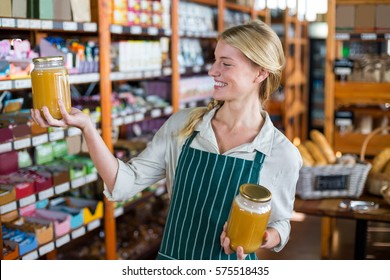 Smiling female staff holding jars of honey in super market - Powered by Shutterstock