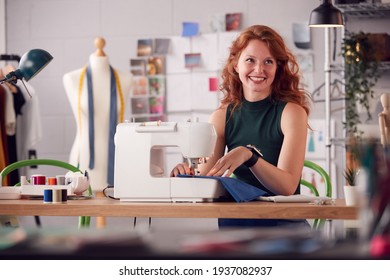Smiling Female Student Or Business Owner Working In Fashion Using Sewing Machine In Studio