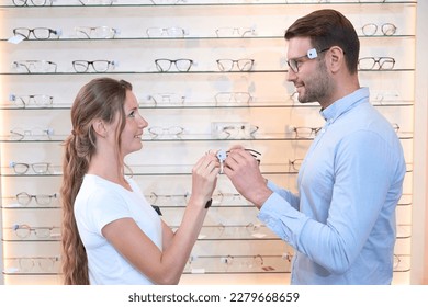 Smiling female talking about new models of eyeglasses with man in optical store
