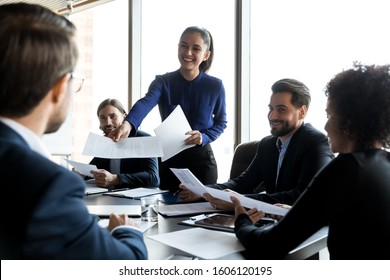 Smiling female team leader share handout materials to diverse multiracial colleagues at meeting, happy woman employee distribute paperwork documents to multiethnic coworkers at company office briefing - Shutterstock ID 1606120195