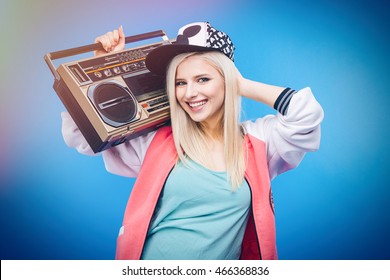 Smiling Female Teenager Holding Retro Boom Box On Blue Background