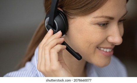 Smiling female telesales agent sell products services remotely working wear wireless headset with microphone close up. Call center operator face, counselling, consultation, contact customers concept