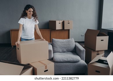 Smiling Female Tenant With Cardboard Boxes Gathering Things For Relocation. Pleased Hispanic Woman Renter Packing Belongings, Preparing To Move In First New Home. Moving, Mortgage Concept.