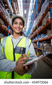 Smiling female worker holding clipboard in warehouse