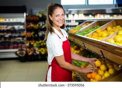 Smiling Female Worker Stocking Lemons In Grocery Store