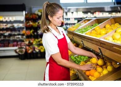 Smiling Female Worker Stocking Lemons In Grocery Store