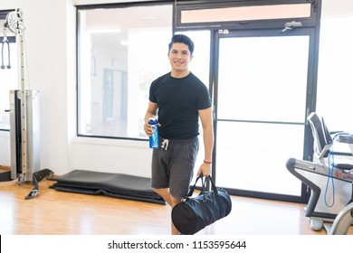 Smiling Fit Man With Water Bottle And Gym Bag Entering In Health Club