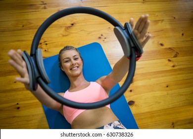 Smiling Fit Woman Exercising With Pilates Ring On Mat In Fitness Studio