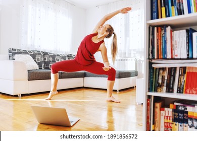 Smiling Fit Yoga Instructor Standing In Goddess Yoga Posture And Having Online Class. Home Interior.