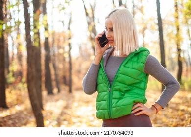 Smiling Fitness Blonde Woman Talking On The Phone In Autumn Forest