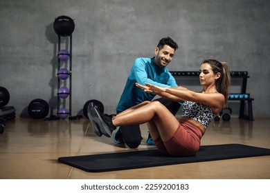 Smiling fitness trainer showing right position to do abs in a gym hiit class. Fitness and gym concept. Horizontal copy space - Powered by Shutterstock