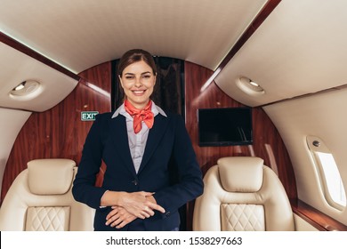 Smiling Flight Attendant In Uniform Looking At Camera In Private Plane 