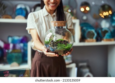 Smiling floral designer showing her florarium with a cork lid