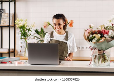 Smiling Flower Shop Owner Working On Laptop Computer. Woman Standing At Counter.