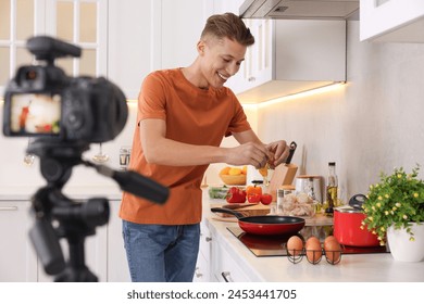 Smiling food blogger cooking while recording video in kitchen - Powered by Shutterstock