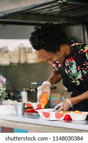 Smiling Food Vendor Hands Food To Waiting Customer