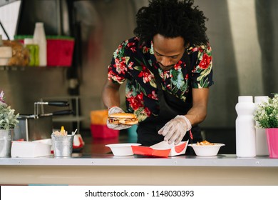 Smiling Food Vendor Hands Food To Waiting Customer