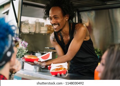 Smiling food vendor hands food to waiting customer