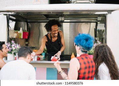 Smiling Food Vendor Hands Food To Waiting Customer