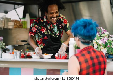 Smiling Food Vendor Hands Food To Waiting Customer