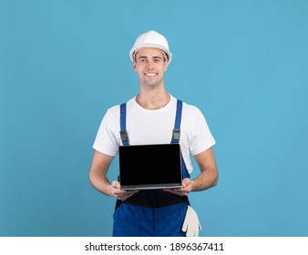 Smiling Foreman Guy In Hard Hat Holding Laptop With Black Screen, Handsome Worker Man Recommending New Website For Online Construction Tools Shopping, Standing On Blue Background, Mockup Image