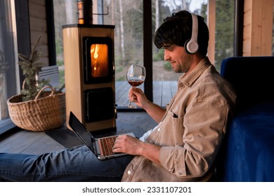 Smiling freelancer drinking wine and using a laptop in the living room sitting on the floor by the fireplace.  - Powered by Shutterstock