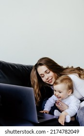 smiling freelancer pointing at laptop while holding little son