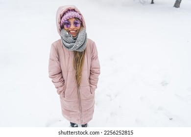 Smiling freezing woman with hands in winter coat pockets standing in the snow. High quality photo - Shutterstock ID 2256252815