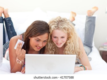 Smiling Friend Girls Shopping Online In A Bedroom