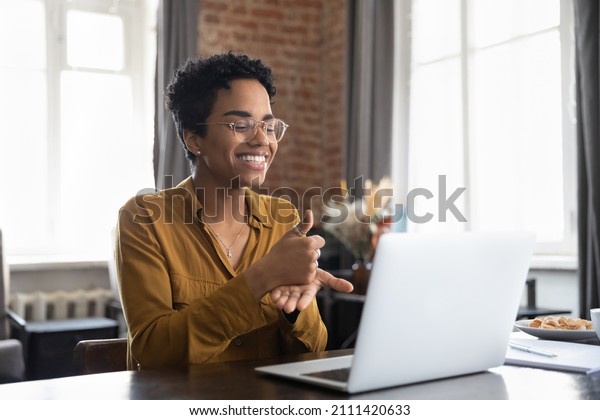 Smiling\
friendly African American therapist in glasses talking on video\
call, using sign language, speaking to patient with hearing\
disability, deafness, showing gestures at\
screen
