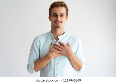 Smiling Friendly Blonde Guy Expressing Gratitude. Grateful Young Caucasian Man Keeping Hands On Chest. Acknowledgement Concept