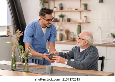 Smiling friendly caretaker serving breakfast to a pensioner - Powered by Shutterstock