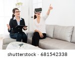 smiling friendly house agent explaining building design when her client using VR technology equipment viewing construction and pointing imitation image asking question.