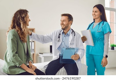 Smiling friendly nurse and male doctor talking with female sick young woman patient supporting her and discussing her treatment in clinic. Medical examination and health care concept. - Powered by Shutterstock