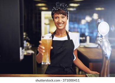Smiling friendly waitress or female bartender serving a pint of draft beer in a pub, conceptual of small business ownership - Powered by Shutterstock