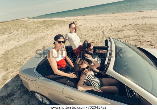 Smiling\
friends driving car near the sea and having\
fun
